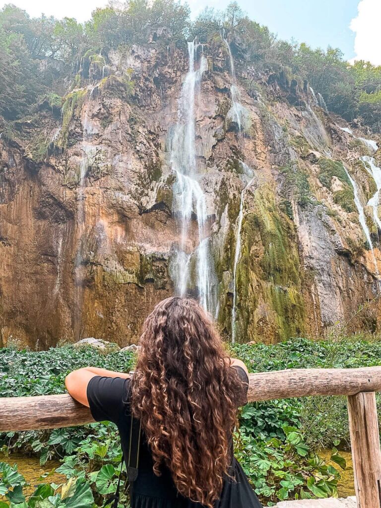 This is an image of the creator of The Purposely Lost standing in front of a slim waterfall at Plitvice National Park in Croatia.
