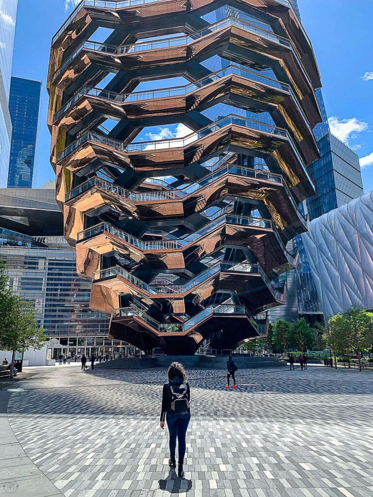This is an image of a woman walking in front of the vessel in Hudson yards in New York City.