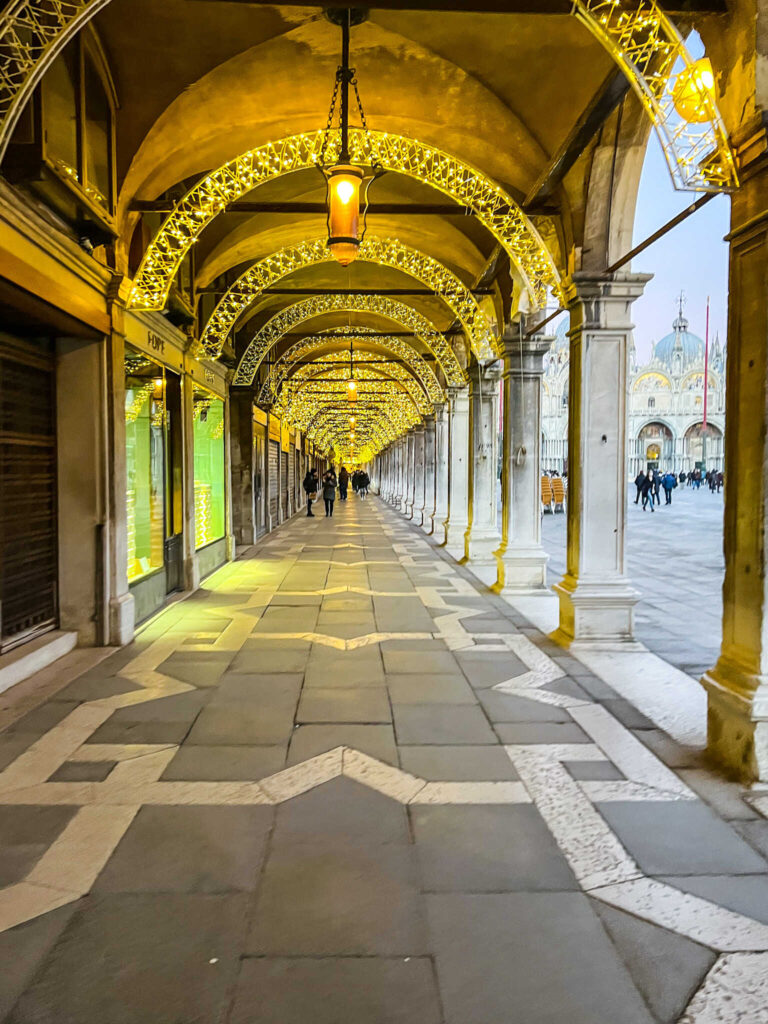 This is an image of a portico in Venice, Italy with Christmas lights hanging above.