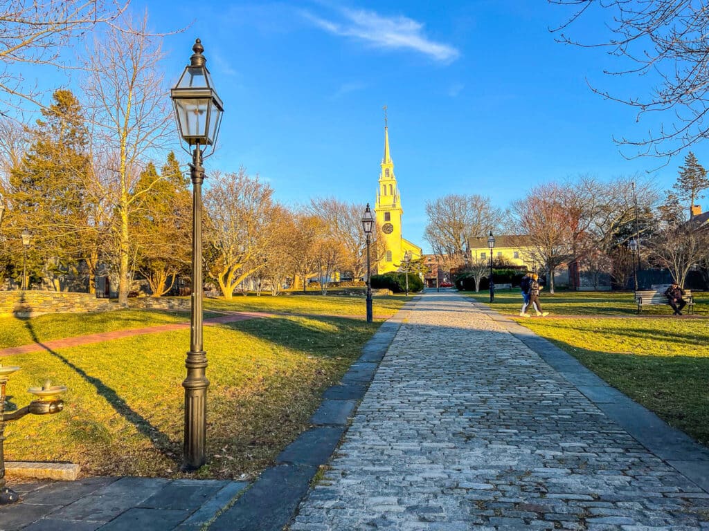 A stone pathway leads to a park with a clock tower in the background during 3 days in Newport.